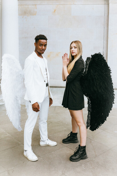 The dark angel holds her hands in prayer to the light angel