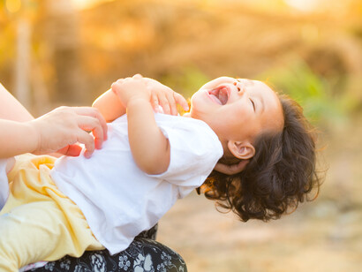 A toddler laughs with their mum