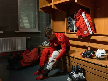A concentrated athlete wearing a red long-sleeve shirt and white knee pads, capturing the intensity, discipline, and commitment required in competitive sport
