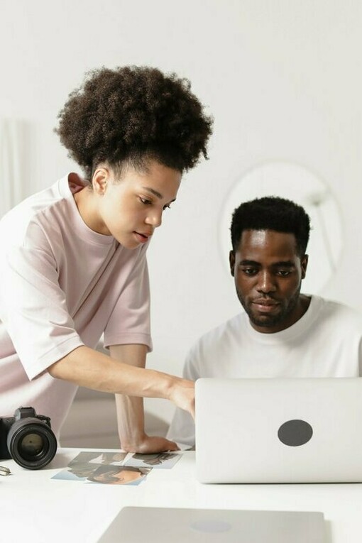 Two creatives reviewing photographs and digital assets together, representing the intentional process of shaping visual identities that build trust