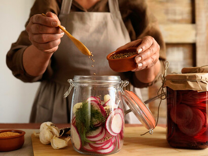 A woman preparing jars of probiotic-rich vegetables, symbolising the need to mindfully nourish gut flora