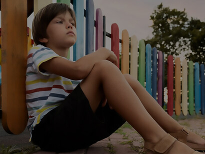 A poignant moment with a medium shot of a pensive boy seated on a bench, lost in daydreams of childhood innocence