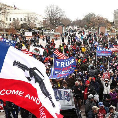 Seguidores de Trump durante el asalto al Capitolio portan banderas con el nombre del expresidente y con una ametralladora