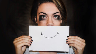 A woman, initially in tears, now holds a paper with a smiley face in front of her, symbolizing her changing emotions and resilience