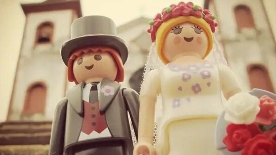 Um casal de Playmobil posa diante de uma igreja em uma cena de casamento criada e fotografada por Maria Moysés. Transformando pequenos bonecos em protagonistas de grandes histórias, o projeto iloveplaymo mostra como imaginação e memória afetiva podem dar novos significados à infância