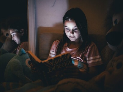 A young reader reading before bedtime, reflecting the quiet joy of discovering new worlds through books