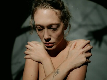 A woman quietly retreating into herself in a dimly lit setting, reflecting the emotional isolation that comparison can create