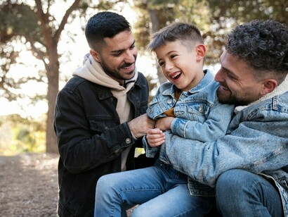 A smiling LGBTQ+ family, featuring same-sex parents and their children