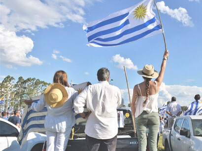 Personas en la calle alzando una bandera de Uruguay