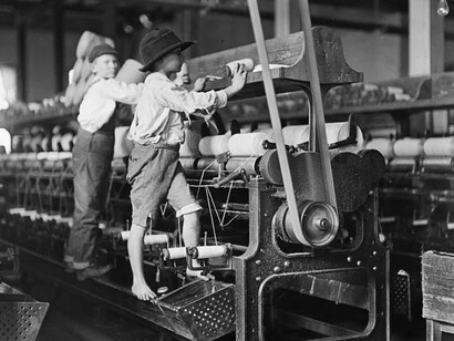 Children with a spinning machine in an early 1900s textile mill