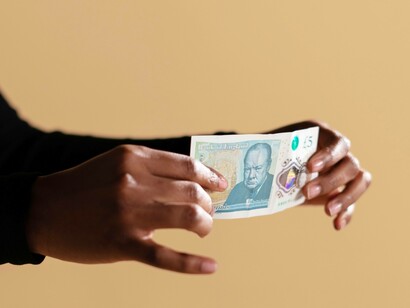 A bank presenting a 5-pound UK sterling note to show his commitment to the British network economy