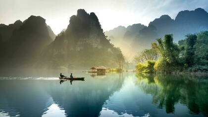 A boat carrying two people glides through the waters of Tuyên Quang City, Vietnam