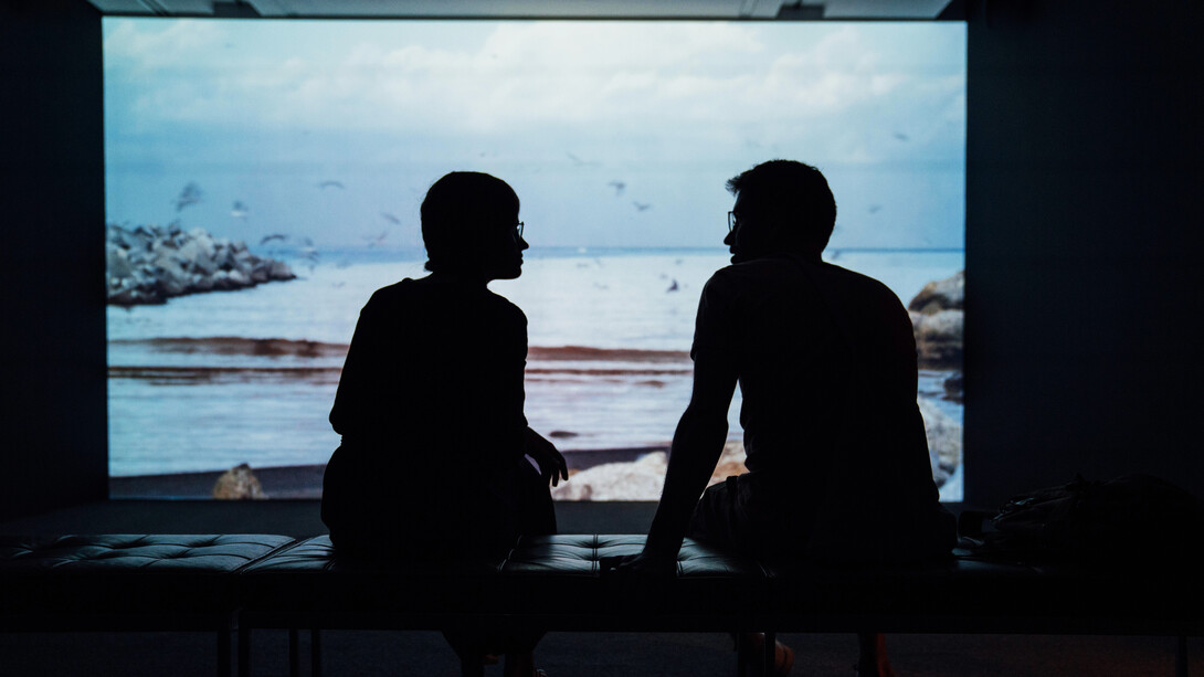 Mujer y hombre tienen una conversación frente que un ventanal que da al mar. Ningún animal tiene conciencia de sí mismo con excepción del Hombre