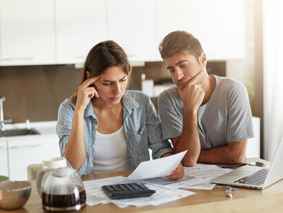 A young couple reviewing their family budget, navigating financial uncertainty and work-related stress
