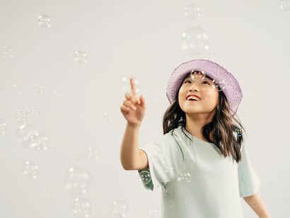 A smiling girl looking at the bubbles, trying to touch them