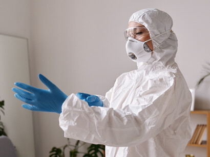 Profesional sanitario con equipo de protección individual mientras se coloca unos guantes