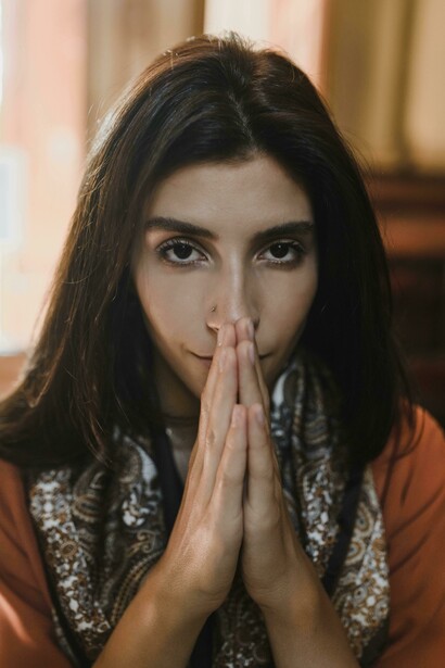 A brunette woman kneeling in a church, praying quietl