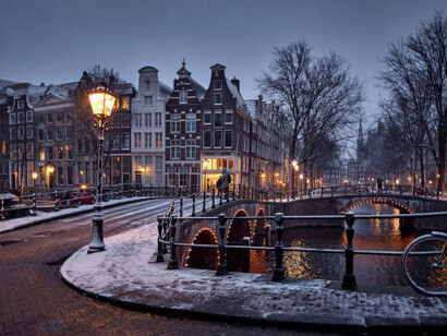 Bicycles parked beside a snowy Amsterdam canal, Netherlands