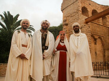 A group of people in distinctive traditional garments and head coverings, reflecting the diversity of cultural expression within a shared heritage