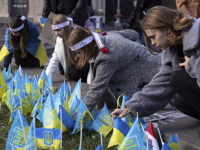 Niñas visitan el memorial para las víctimas de la guerra en Ucrania instalado con motivo de su primer aniversario