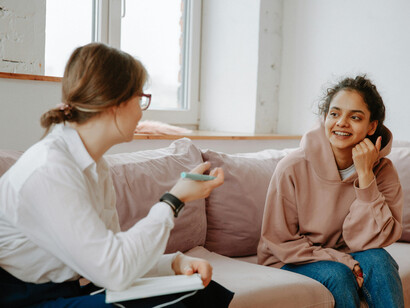 Young woman talking with a therapist, representing teenage mental health, overwhelmed teens, and stressed teen girls