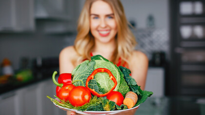 Capture the essence of a healthy lifestyle with an image of a sports girl in a kitchen surrounded by vibrant fruits and vegetables, embodying the principles of a plant-based diet and promoting longevity