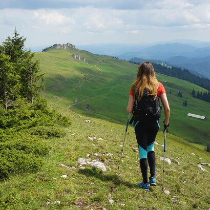 Donna che fa trekking in un paesaggio montano: “Trekking e ferrate o anche solo una passeggiata sulla battigia offrono incredibili vantaggi per il corpo”