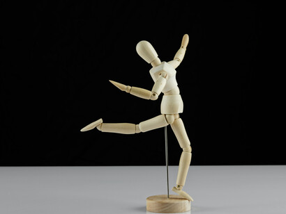 A simple wooden figure becomes a symbol of manipulation, as if unseen hands are pulling the strings of a larger crowd