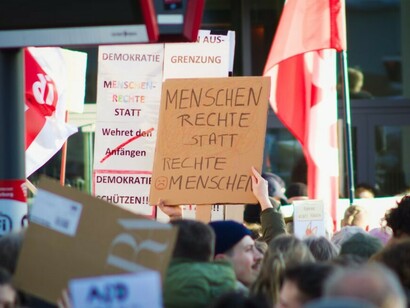 A crowd of people holds up signs and placards during an anti-AfD protest in Marburg, Germany