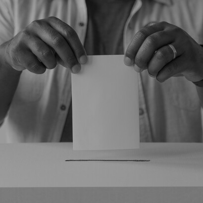 A voter’s hands carefully place a ballot into the box, symbolizing the democratic power at play in Chile’s upcoming 2025 presidential election