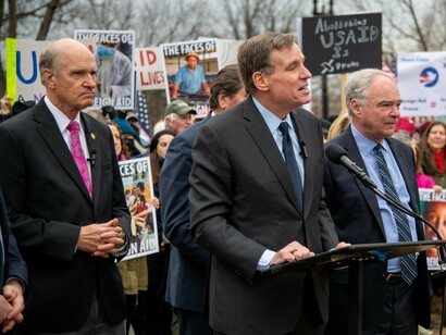 Senator Mark Warner stands with USAID workers and supporters at a public rally, addressing concerns over international aid policies and funding cuts on February 5, 2025