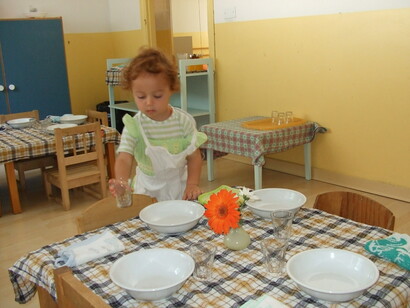 Un bambino apparecchia la tavola