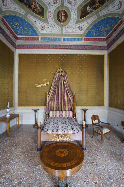 Letto stile Impero con tavolino rotondo, primi decenni sec. XIX, impiallacciato in noce e in radica di noce. Sul piano intarsi in noce su fondo di
acero. Fusto tornito a balaustro con diverse strozzature, intaglio a foglia di acanto laccata verde su base triangolare filettata in acero. Cassetto.