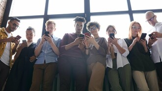 Un groupe de jeunes adultes fait défiler leurs téléphones, inconscients de leur environnement