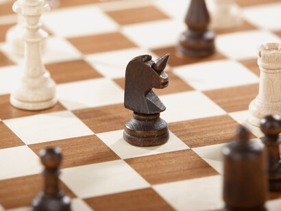Un caballo de las fichas 'negras' de un ajedrez acecha a la reina de las 'blancas'