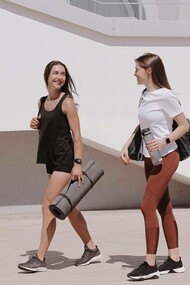 Two friends walk with yoga mats
