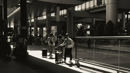 People arriving and departing with suitcases, representing the human movement behind economic growth
