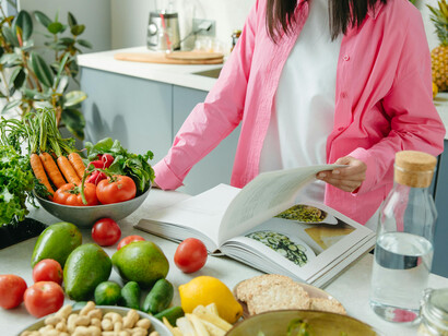 A person in a pink overshirt holding a tomato during healthy meal preparation