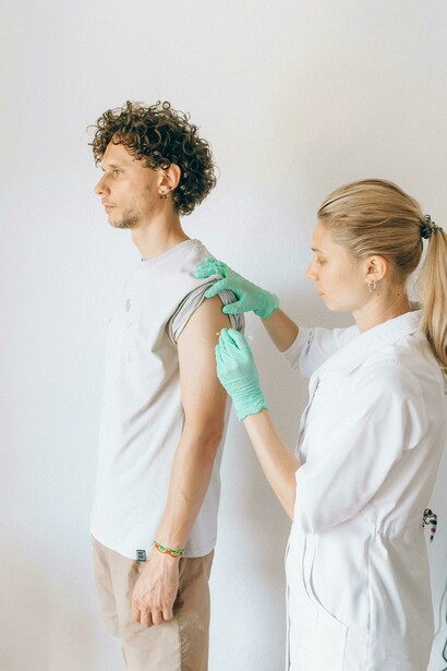 A healthcare administers a vaccine to a standing patients during a vaccination drive