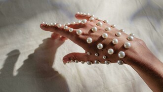 Pérolas usadas como adorno em mão. Este artigo explora a versatilidade das pérolas na moda atual e como elas estão a ser reinterpretadas por designers e estilistas
