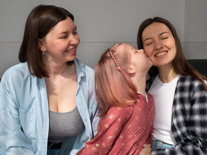 Two mothers spending quality time with their daughter at home, reflecting the love and bond within LGBTQ+ families
