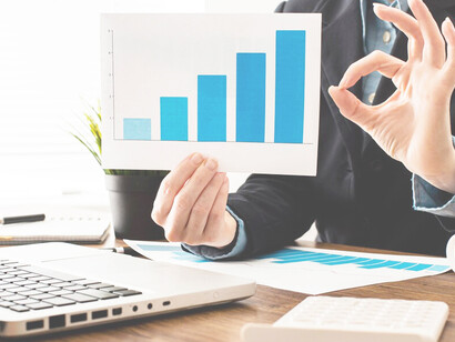 A businessman making an "OK" sign while holding a growth chart, representing career goals, targets, and work-life balance