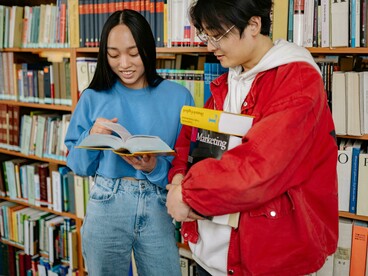 A man and a woman talking inside a library, exchange students