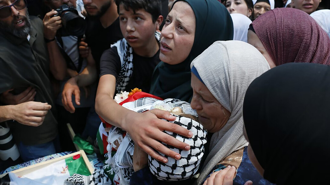 A group of people gathered together, with women visibly grieving, amid the Gaza conflict