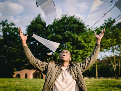 A man celebrating his success by throwing papers in the air