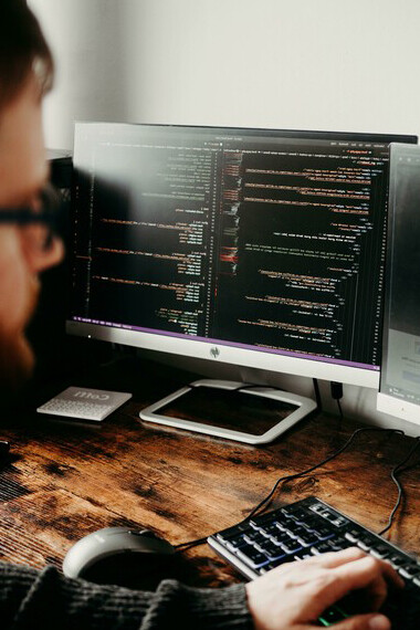 A man sitting at a desk working on his computer, focused on coding