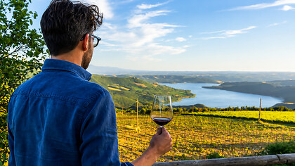 Man enjoying a glass of dessert wine in a Tuscan vineyard, surrounded by the rolling countryside of Italy