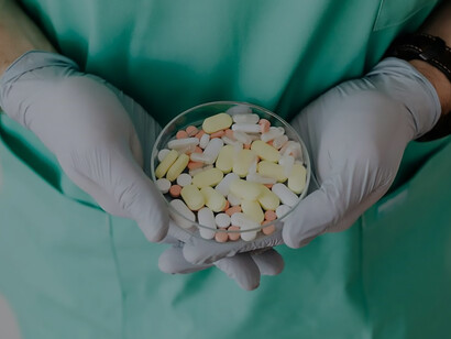 A physician carefully cradles a multitude of medications in their hand