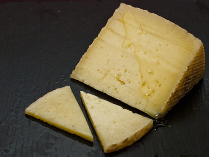 Queso manchego con su característica forma cilíndrica, su típico dibujo de flor y sus laterales zigzagueantes