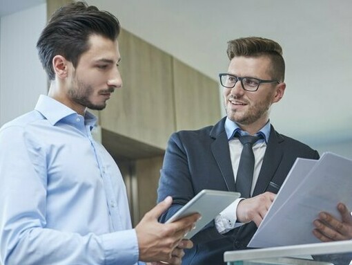 Two businessmen reviewing documents—a reminder of how shareholder decisions can quietly shape the course of countless lives.